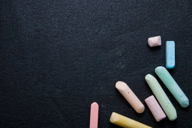 siyah bir arka plan üzerinde birkaç renkli boya kalemleri, tebeşir, tebeşir ile asfalt çizmek, kopya alanı, üst görünümü