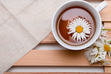 ahşap tepsi beyaz arka plan izolasyon üst görünüm kopya alanı papatyalar ile bej kumaş üzerinde papatya çay ile fincan