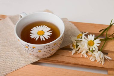 ahşap tepsi beyaz arka plan izolasyon üst görünüm kopya alanı papatyalar ile bej kumaş üzerinde papatya çay ile fincan