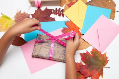 çocuk el şükran mevcut pembe bir kurdele yay bağlar, hediyeler kutuları, zarflar ve beyaz bir masa üzerinde sonbahar yaprakları, kopya alanı, üst görünümü