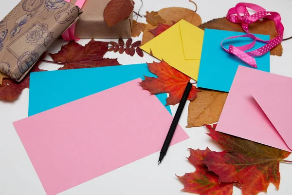 envelopes, cards, thanksgiving gifts, beautiful autumn maple leaves on a white table, copy space. top view, flat lay, ribbons, gift wrapping, send a letter