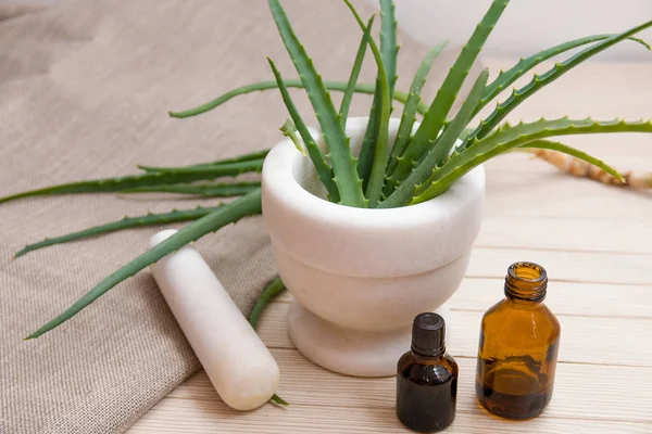 natural medicine, aloe in a white stone mortar, wooden plank table, beige background, linen fabric, small bottles of dark glass, treatment of illness