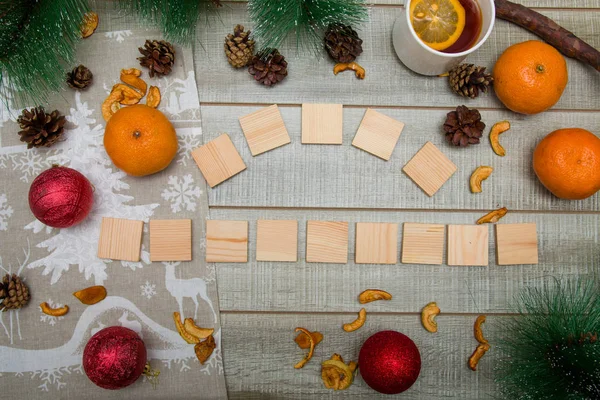 wooden boxes with the inscription Merry Christmas, pine branches, Christmas toys, tangerines, tea with lemon, Christmas mood, top view, wooden background
