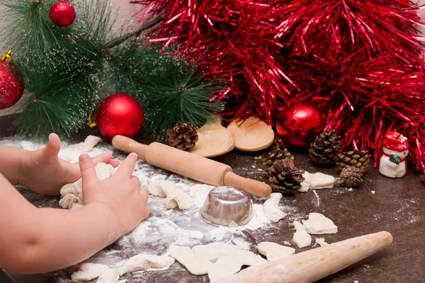 ittle girl, a boy kneads dough for Christmas cookies against bright Christmas decorations and kitchen utensils