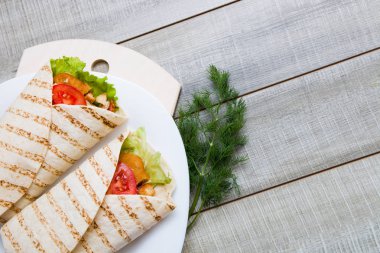 Beyaz bir tabakta iki sezar yuvarlanıyor, tahta gri arka plan, kopyalama alanı, tahta kesme tahtası