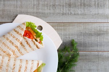 Pide ekmeğinde tavuk pirzolası ve sebzeler, beyaz bir tabakta, ahşap gri arka plan, kesme tahtası, dereotu, Sezar rulosu, tavuk rulosu, fotokopi yeri, üst manzara