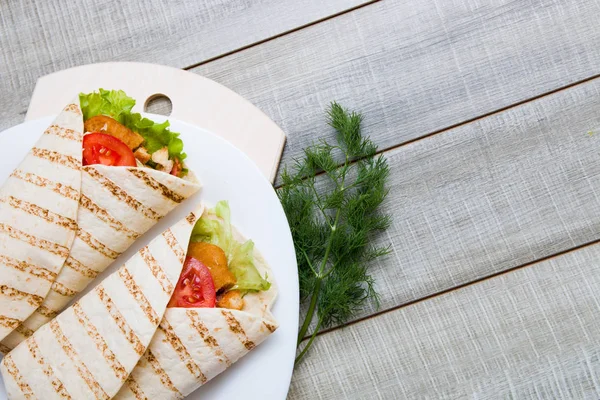 Beyaz bir tabakta iki sezar yuvarlanıyor, tahta gri arka plan, kopyalama alanı, tahta kesme tahtası