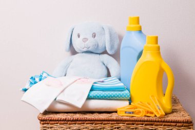 Çamaşır jeli ve kumaş yumuşatıcı, renkli çocuk iç çamaşırı yığını ve çocuk oyuncağı, kirli giysiler için hasır sepette kurutmak için elbise askıları.