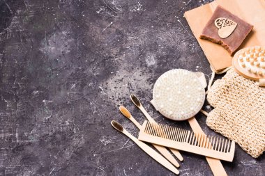 Kuru anti-selülit masaj fırçası, örgü pamuk sünger, doğal kakao sabunu ve bambu diş fırçası, ahşap tarak ve siyah desenli arka planda vücut masajı.