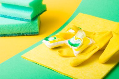 Plastik eldivenler, bulaşık makineleri için kapsüller, yeşil ve sarı arka planda süngerler, fotokopi makinesinin görüş alanı, bulaşık yıkama ile bulaşık makinesi arasında seçim