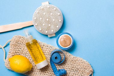 Limon, vücut yağı, mezura, el bezi, mavi arka planda ev yapımı fırça, anti-selülit masaj seti.