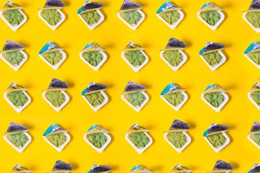 Birkaç wasabi deseni küçük plastik kaplarda rulo ve suşi teslimatı için, sarı arka plan fotokopi alanı, wasabi sosu paketleri