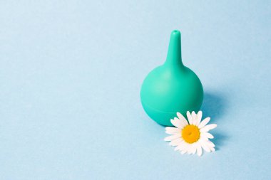 green little enema and chamomile on blue background clipart