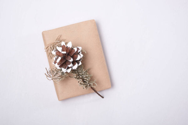 dried fir branch and pine cone on a gift box wrapped in eco paper on a gray background top view place copy eco friendly lifestyle, eco christmas and new year