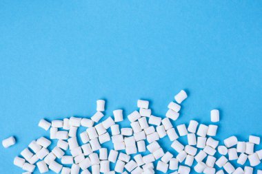 Küçük beyaz şekerlemeler mavi arkaplan fotokopi alanına saçılmış.