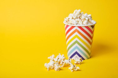 Sarı arka planda parlak tatil kağıt bardağında patlamış mısır.