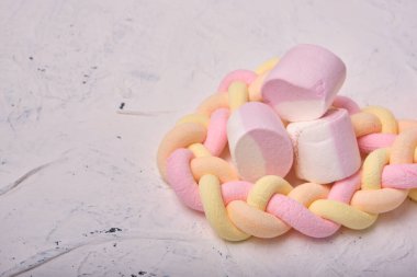 Beyaz arka planda birkaç marşmelov, uzun örülmüş marşmelovlar, meyve aromalı marşmelovlar, kopya alanı.