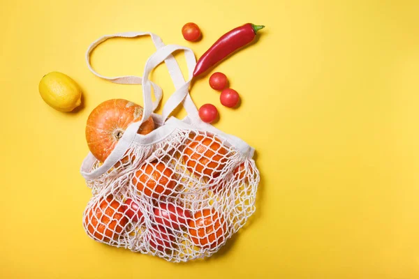 Juicy and fresh vegetables and fruits in ecological cotton reusable string bag, alternative to plastic bags, on white background. top view copy space