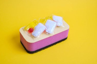 Bulaşık makineleri için jel kapsülleri ve süngerler, fotokopi makinesinin bulunduğu yerin yeşil ve sarı arka planında, bulaşık yıkama ile bulaşık makinesi arasında seçim