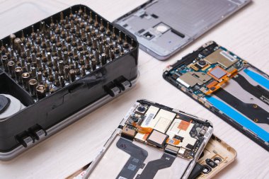 Siyah bir kutuda tornavida parçaları, eldivenler, bozuk akıllı telefonlar ve telefonunuzun ve tabletinizin camını değiştirmek için gerekli aletler.