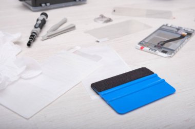Telefon ekranını ahşap masaya yapıştırmak için spatula, telefon ekranındaki camları spatulayla temizlemek için telefon tamir konsepti.