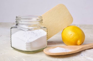 Büyük bir tahta kaşık üzerinde sitrik asit, sünger, teneke kutu içinde soda ve eko temizleme için limon toksik olmayan deterjan, iki kavram, sıfır atık yaşam tarzı