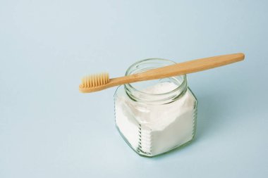 Bambu diş fırçası ve açık mavi arka planda bir kutu soda.