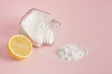 Pembe arka planda cam bir kavanozdan dökülen limon ve soda.