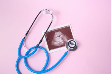 Pembe arka planda tıbbi steteskop ve embriyo resmi.