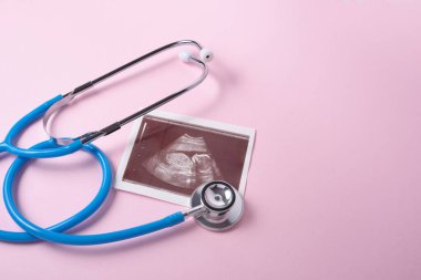 Pembe arka planda embriyonun stetoskop ve ultrason taraması, hamilelik konsepti