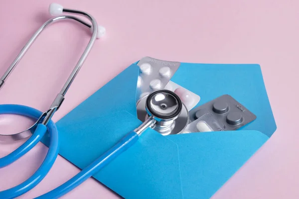 Pil Dalam Amplop Biru Dan Stetoskop Medis Pada Latar Belakang — Stok Foto