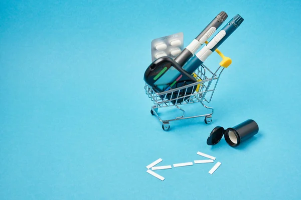 Diabetes concept. Diabetic supplies in shop trolley on a blue background.