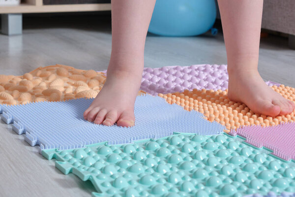 the child walks on the mat for massage of the feet at home. Prevention of flat feet and hallux valgus Orthopedic massage puzzle mats for the development of children.