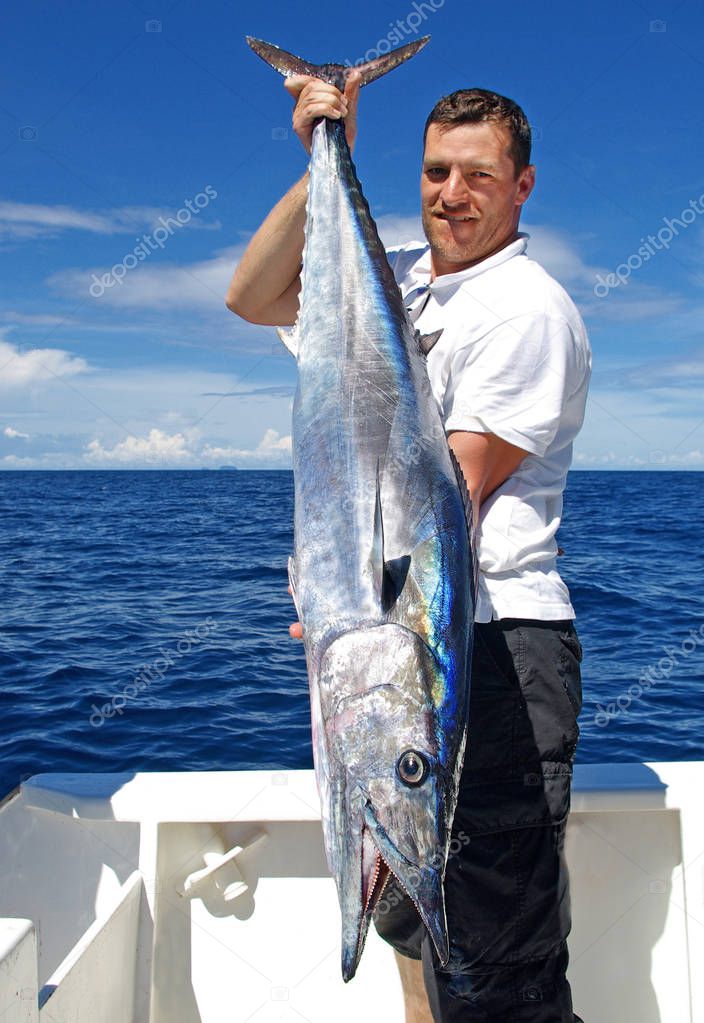 Deep sea fishing, big game fishing. Lucky  fisherman holding a beautiful wahoo fish.