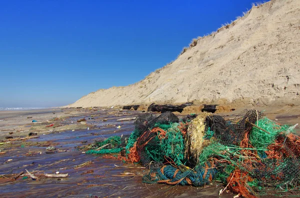 前景にプラスチック汚染と漁網とフランスの大西洋西海岸のビーチ上の大きな眺め 漁網は鯨類にとって危険です — ストック写真