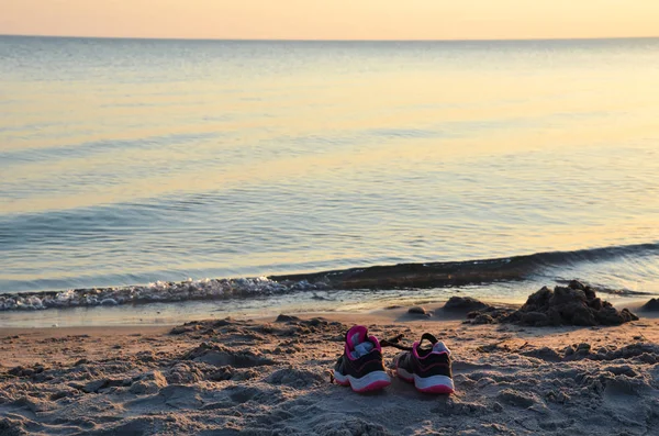 Shoes by seaside on a beach by sunset — Stock Photo, Image