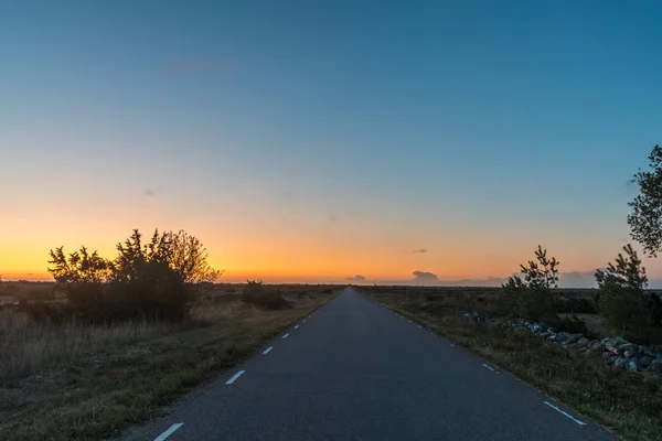 Salida del sol en un camino rural en un paisaje estéril plano — Foto de Stock