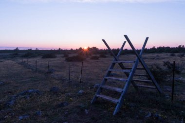 Geleneksel ahşap stil gün batımına kadar bir çitin üzerinde Büyük çorak arazide Stora Alvaret İsveç 'in Oland adasında
