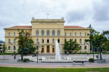 Szeged, Macaristan, 27 Haziran: Szeged Üniversitesi nerede öğrenciler oturup 27 Haziran 2018 Meydanı ' nda bir çeşme ile ana bina.