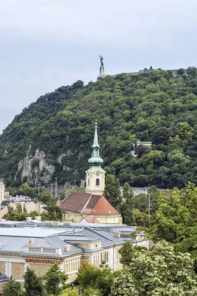 Gellert Hill ve Budapeşte'özgürlük heykeli görünümünü. Ön planda bir saatli kilise kule olduğunu.