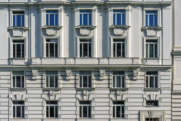 Rectangular windows on the facade of a gray building with a bas-relief.