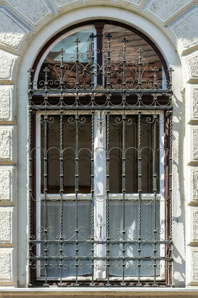 Beyaz bir çerçeve ve arch adlı demir parmaklıkları ve cam yansıması ile beyaz bir duvar açık ile pencere.