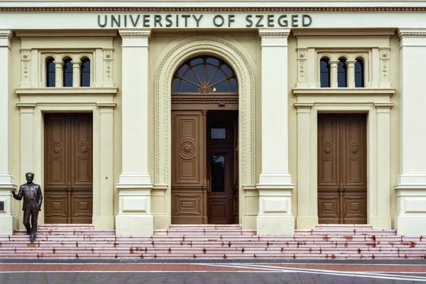 Szeged, Macaristan, 28 Haziran: Görüntü Szeged Üniversitesi pembe bir taş adımları üzerinde 28 Haziran 2018 üzerinde duran bir öğretmen resmeden bir rakam ile bina ana giriş.