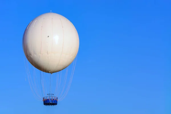 一个白色的气球 带着一只蓝色的圆形机舱 在明亮的蓝天上 没有人的形象 — 图库照片
