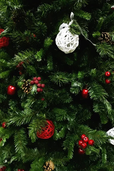 Bir Noel ağacı parçası kırmızı ve beyaz Noel oyuncaklar ve çam kozalakları ile dekore edilmiş.