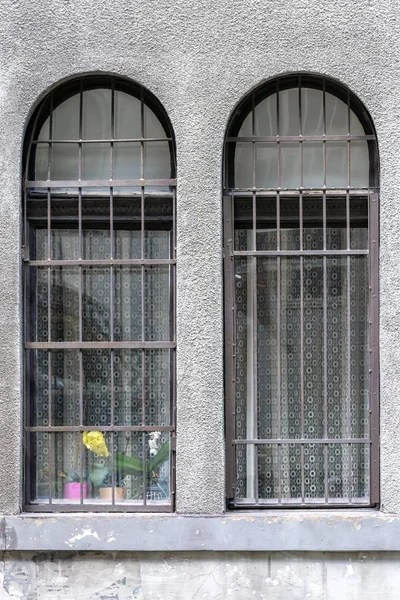 Två Fönster Med Båge Och Ett Galler Mot Grå Vägg — Stockfoto