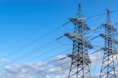 Two supports of high-voltage transmission line with electric power wires on the blue sky background. clipart