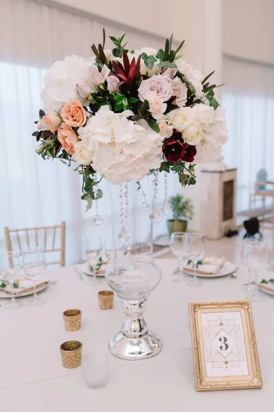 Magnificent, volume bouquets of flowers in high glass vases. Wedding flowers on tables for guests