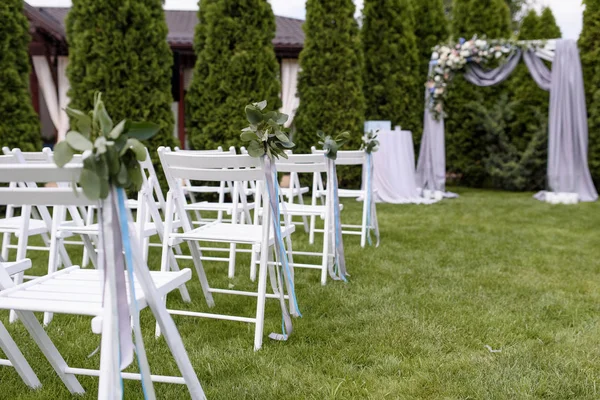 Green buttonholes on white chairs. — Stock Photo, Image