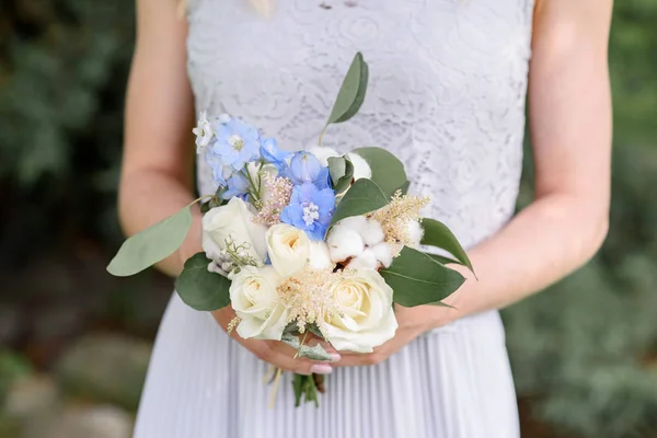 White roses and blue flowers in the bouquet of the bridesmaid. — Stock Photo, Image